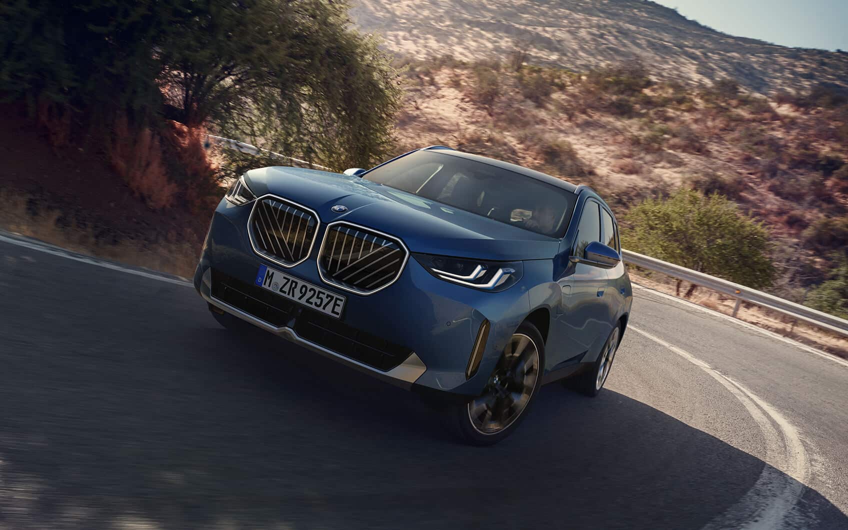 Blauer BMW X3 Plug-in-Hybrid auf Bergstraße