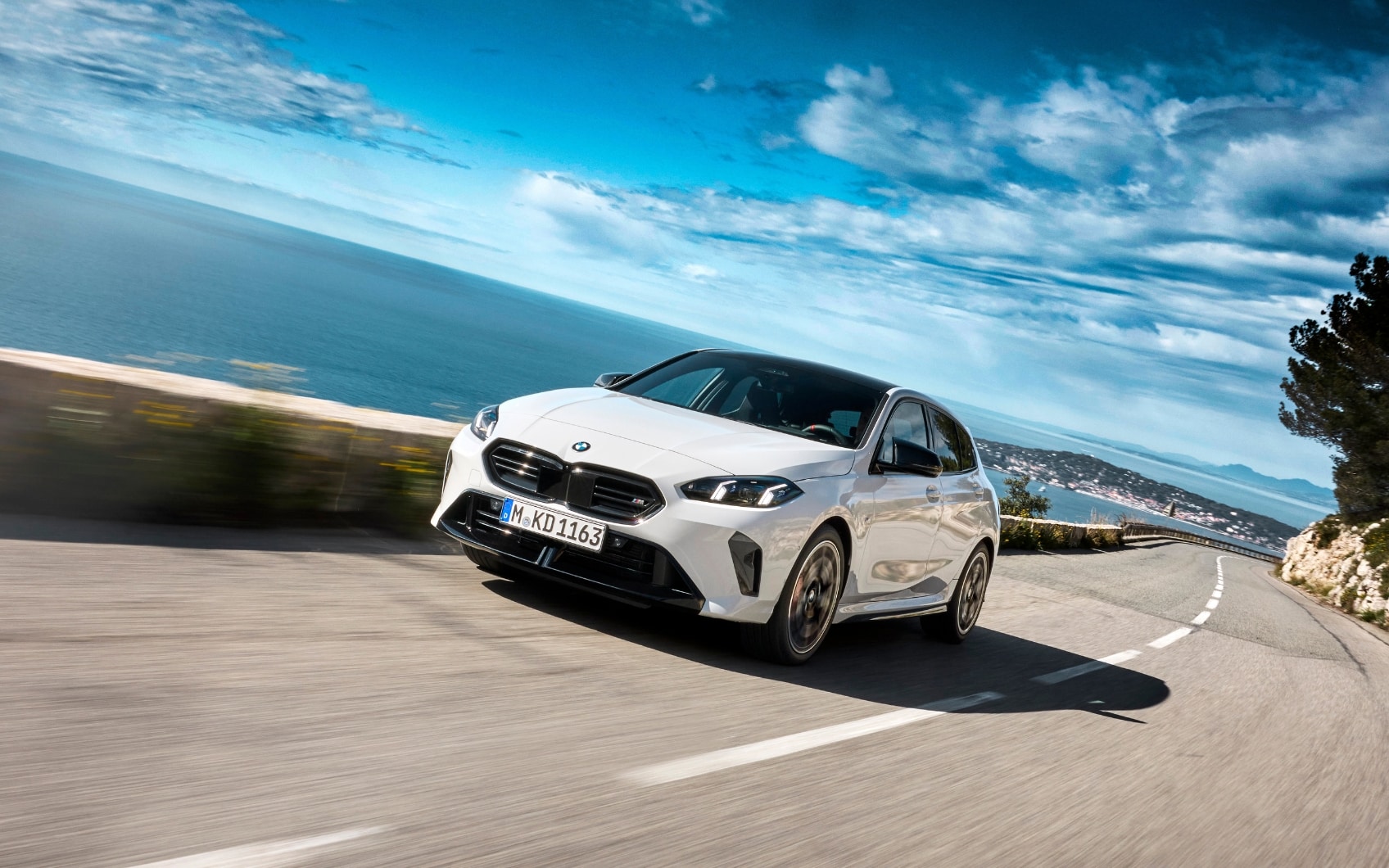 Weißer BMW 1er auf Küstenstraße am Meer